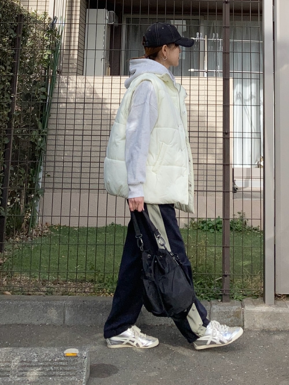 ホワイト系のダウンベスト、グレー系のパーカー、ブルー系のスウェットパンツを着用したレディースの冬コーディネートの2枚目の写真