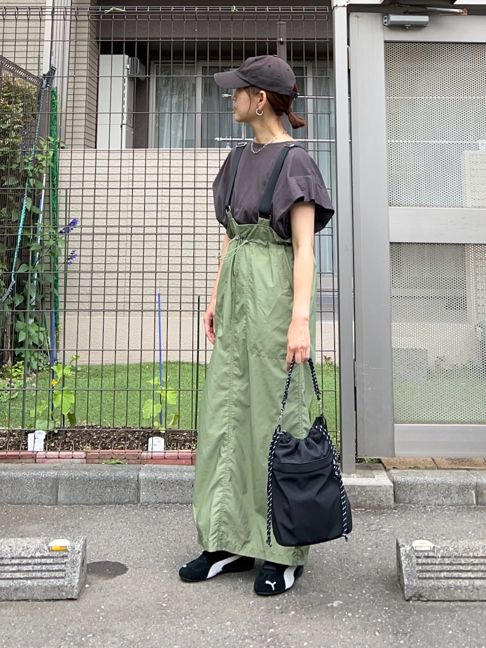 グリーン系のジャンパースカート、シルバー系のトートバッグ、ブラック系のスニーカーを着用したレディースの夏コーディネートの2枚目の写真