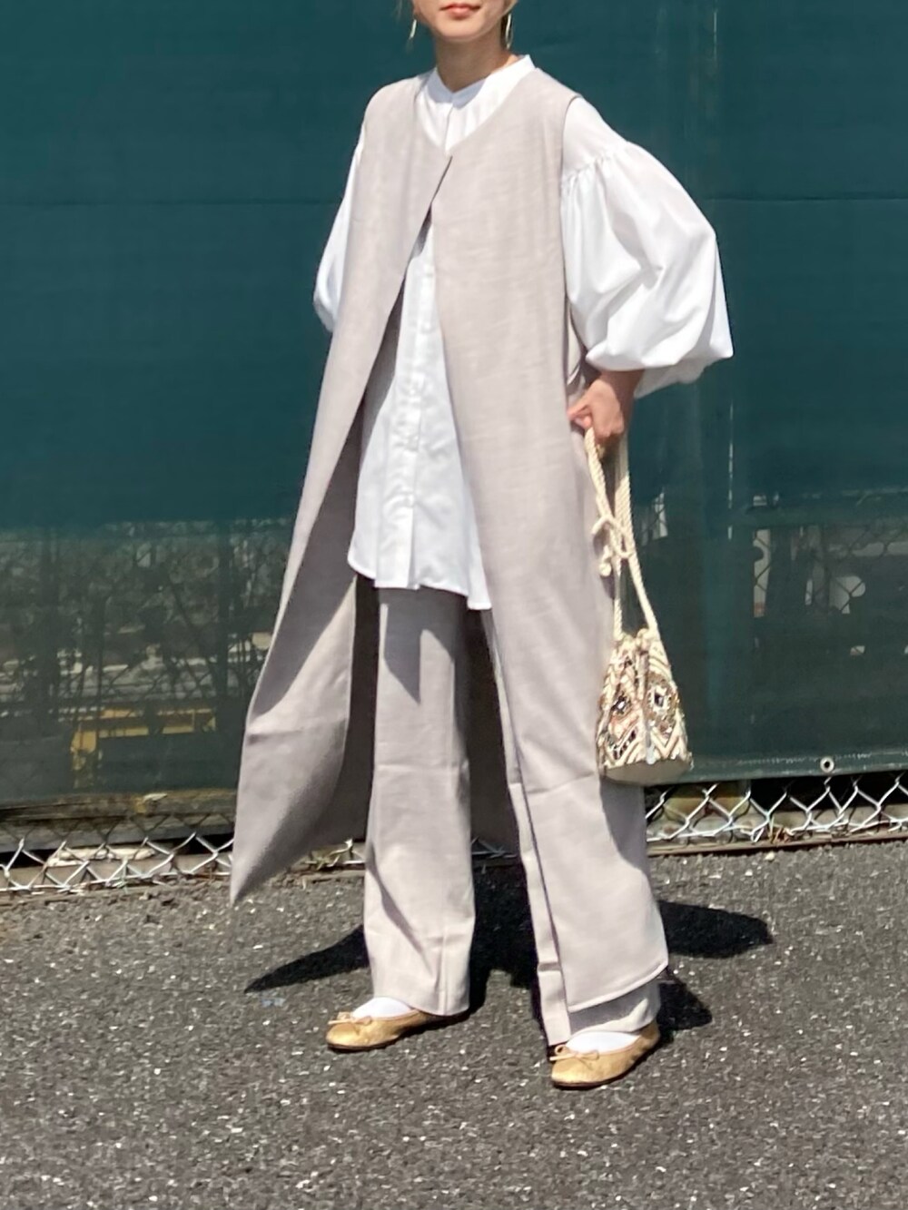 ホワイト系のシャツ/ブラウス、ベージュ系のベスト、ベージュ系のスラックスを着用したレディースの春コーディネートの2枚目の写真