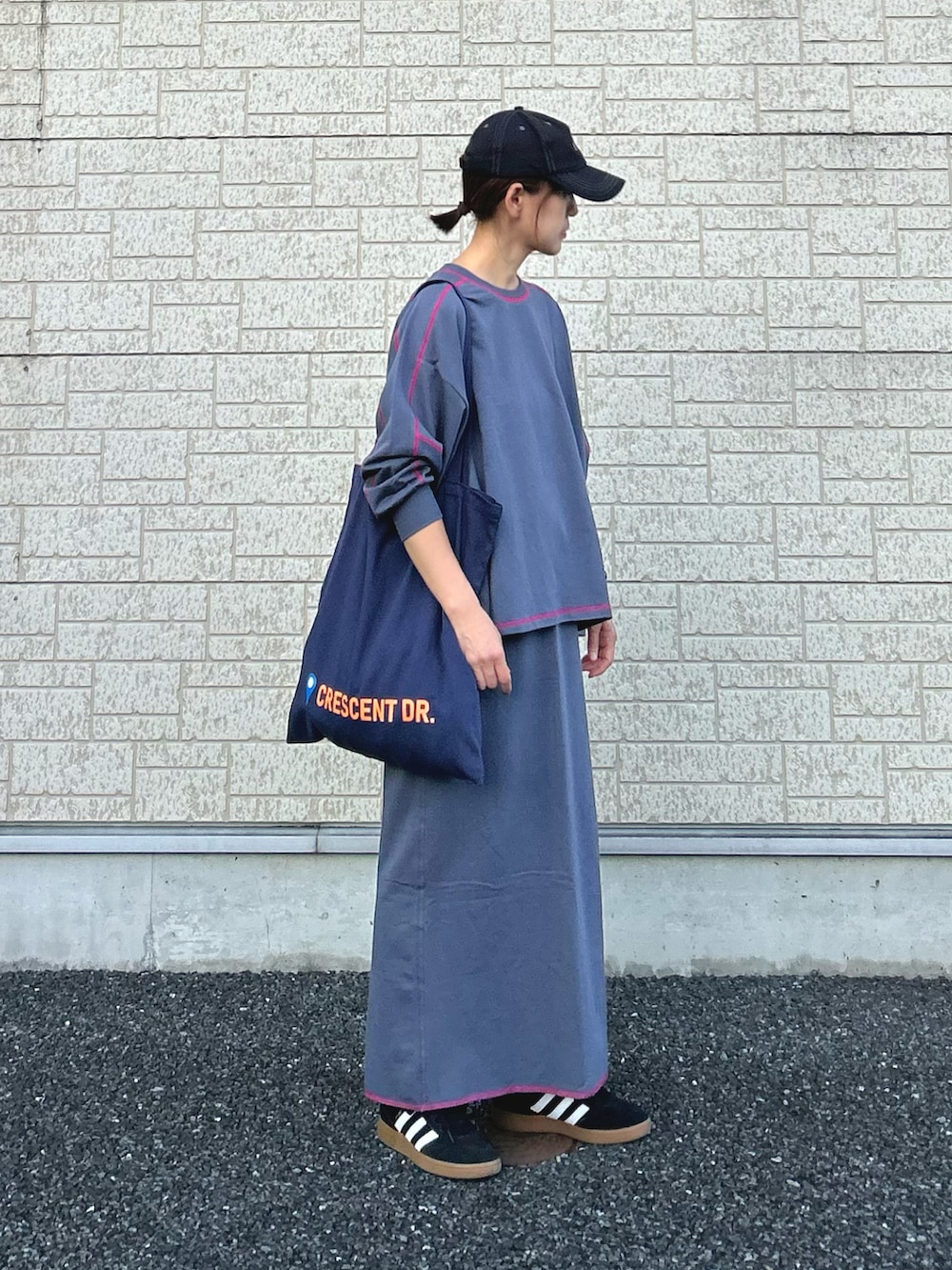 グレー系のTシャツ/カットソー、グレー系のスカート、ブルー系のトートバッグを着用したレディースの秋コーディネートの2枚目の写真