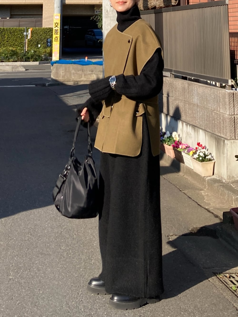 グリーン系のベスト、ブラック系のワンピース、ブラック系のショルダーバッグを着用したレディースの冬コーディネートの2枚目の写真