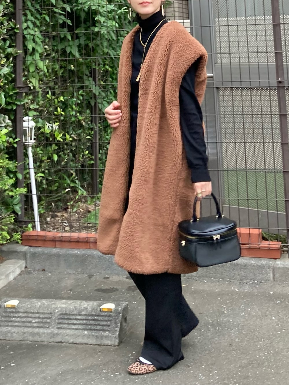 ブラウン系のベスト、ブラック系のショルダーバッグ、ゴールド系のネックレスを着用したレディースの秋コーディネートの3枚目の写真