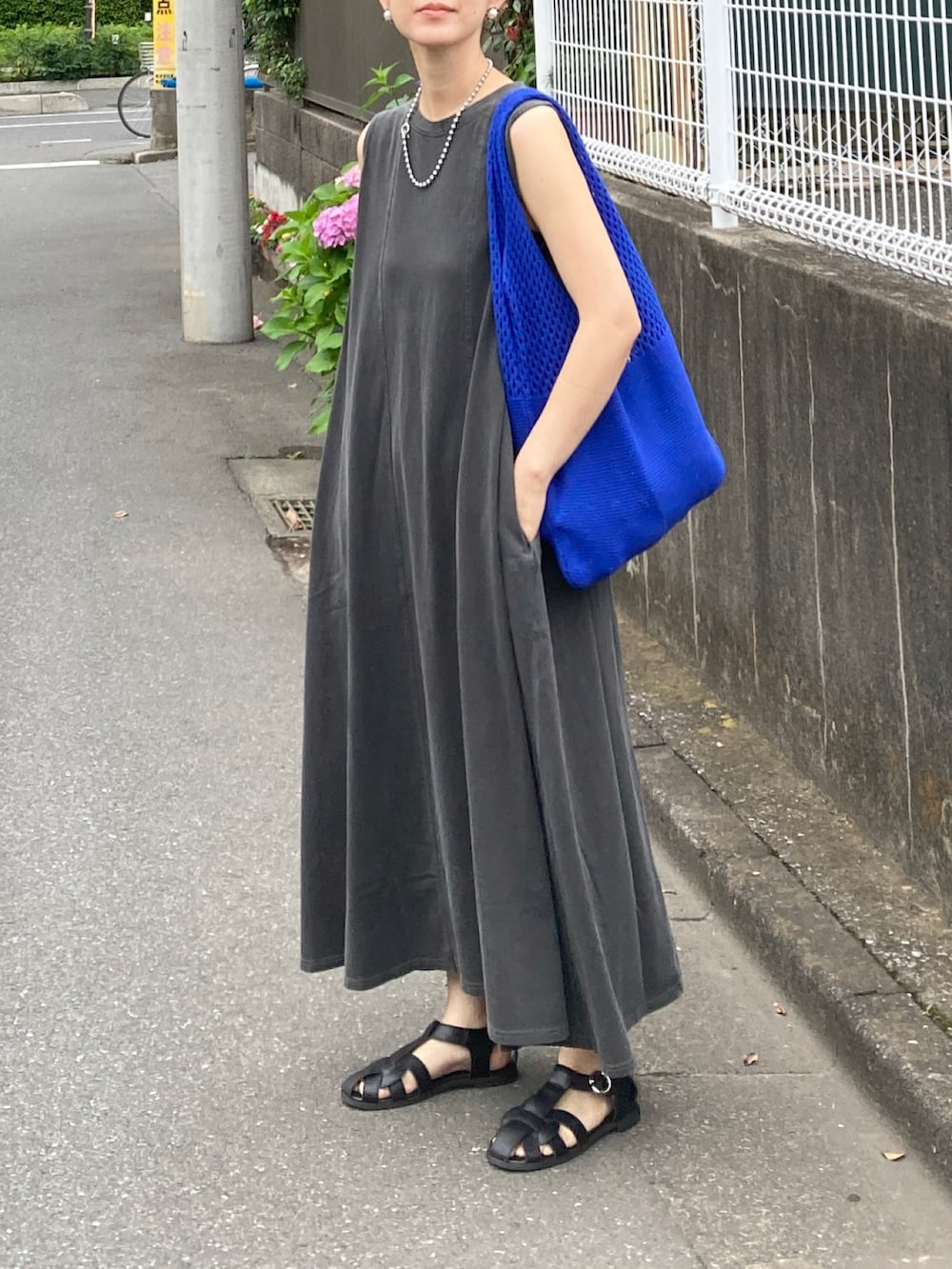 グレー系のワンピース、ブルー系のショルダーバッグ、ブラック系のサンダルを着用したレディースの夏コーディネートの2枚目の写真