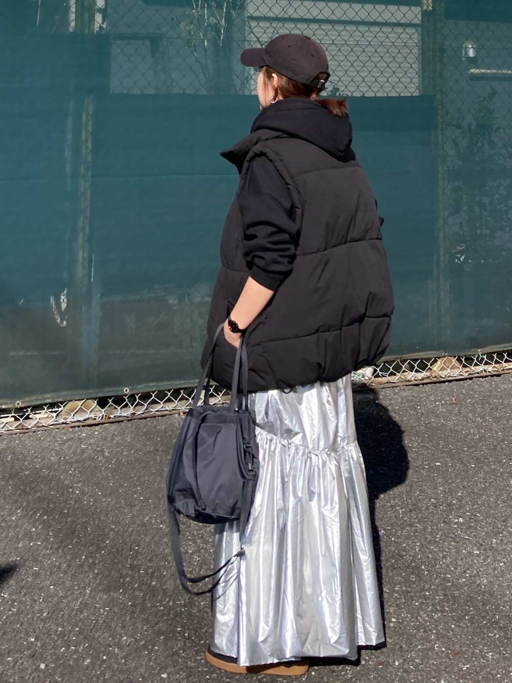 ブラック系のダウンベスト、シルバー系のスカート、ブラック系のパーカーを着用したレディースの冬コーディネートの4枚目の写真