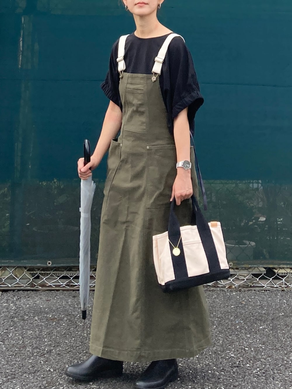 ブラック系のTシャツ/カットソー、グリーン系のジャンパースカート、ホワイト系のトートバッグを着用したレディースの秋コーディネートの3枚目の写真