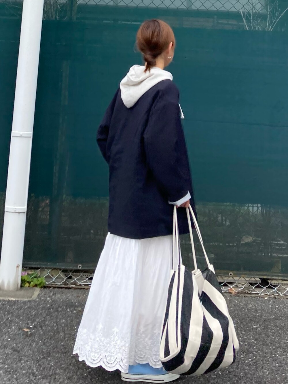 ベージュ系のパーカー、ホワイト系のスカート、ブラック系のトートバッグを着用したレディースの春コーディネートの5枚目の写真