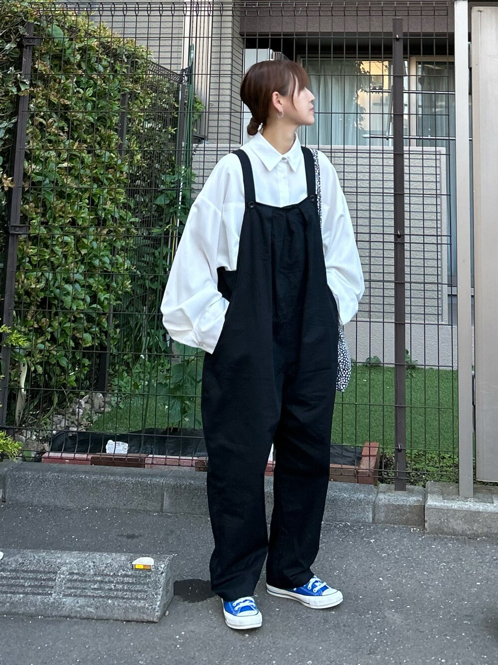 ホワイト系のシャツ/ブラウス、ブラック系のサロペット/オーバーオール、ブルー系のスニーカーを着用したレディースの春コーディネートの2枚目の写真