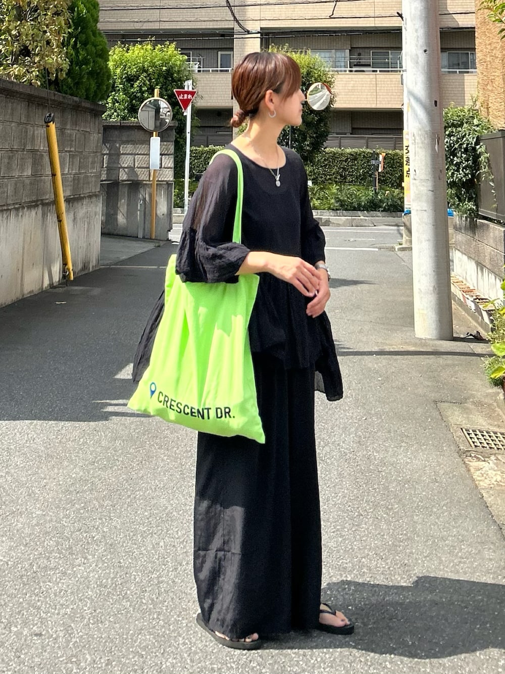 グリーン系のトートバッグ、ブラック系のシャツ/ブラウスを着用したレディースの夏コーディネートの3枚目の写真