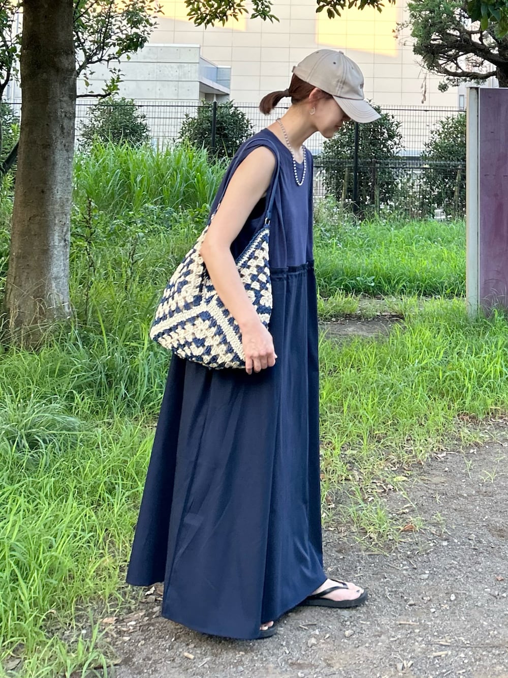 ブルー系のワンピース、ブルー系のかごバッグ、ベージュ系のキャップを着用したレディースの夏コーディネートの2枚目の写真