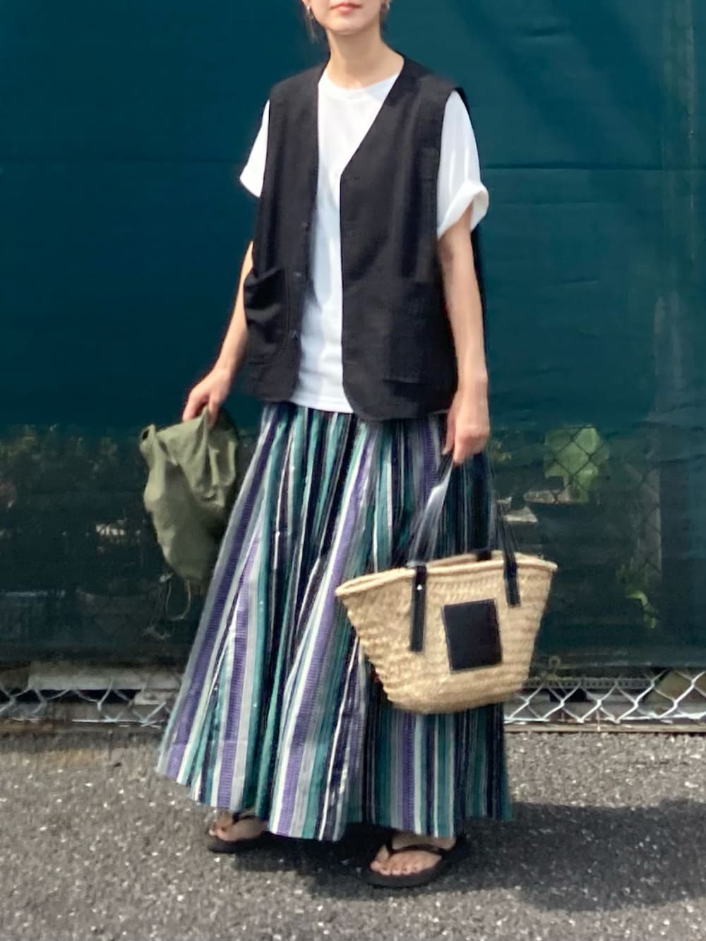 ホワイト系のTシャツ/カットソー、グリーン系のスカート、ブラック系のかごバッグを着用したレディースの夏コーディネートの3枚目の写真