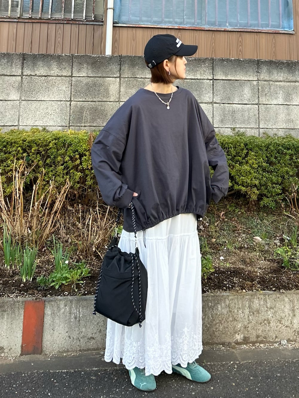 グレー系のTシャツ/カットソー、ブラック系のトートバッグ、ホワイト系のスカートを着用したレディースの冬コーディネートの2枚目の写真