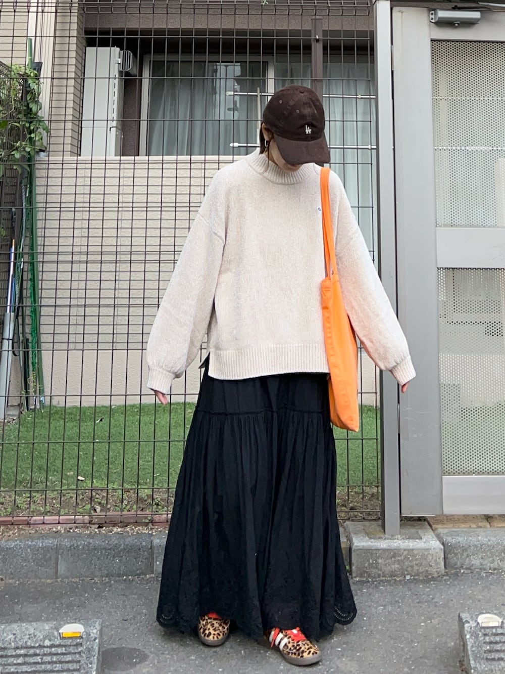 ベージュ系のニット/セーター、ブラック系のスカート、オレンジ系のトートバッグを着用したレディースの冬コーディネートの3枚目の写真