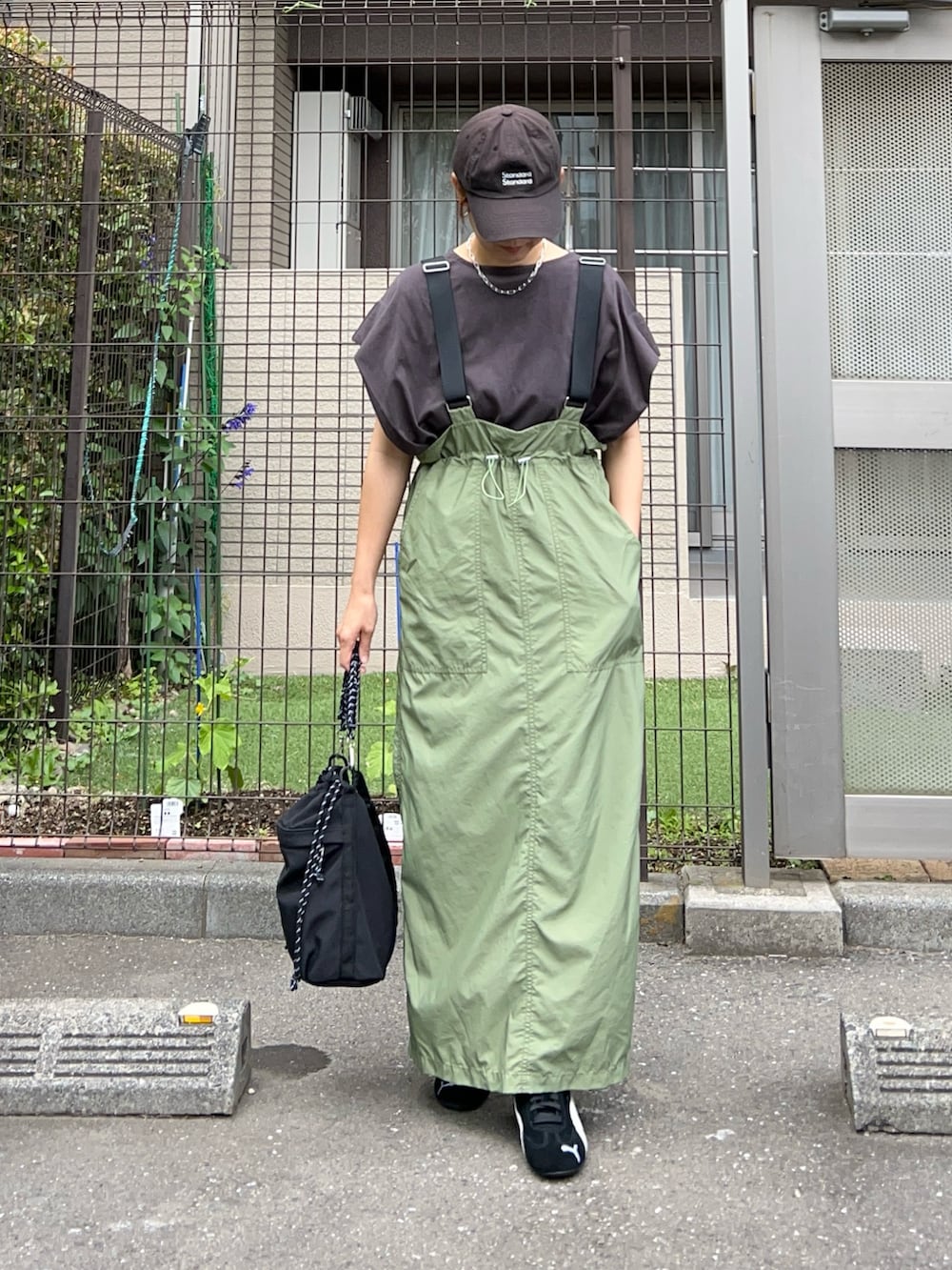 グリーン系のジャンパースカート、シルバー系のトートバッグ、ブラック系のスニーカーを着用したレディースの夏コーディネートの3枚目の写真