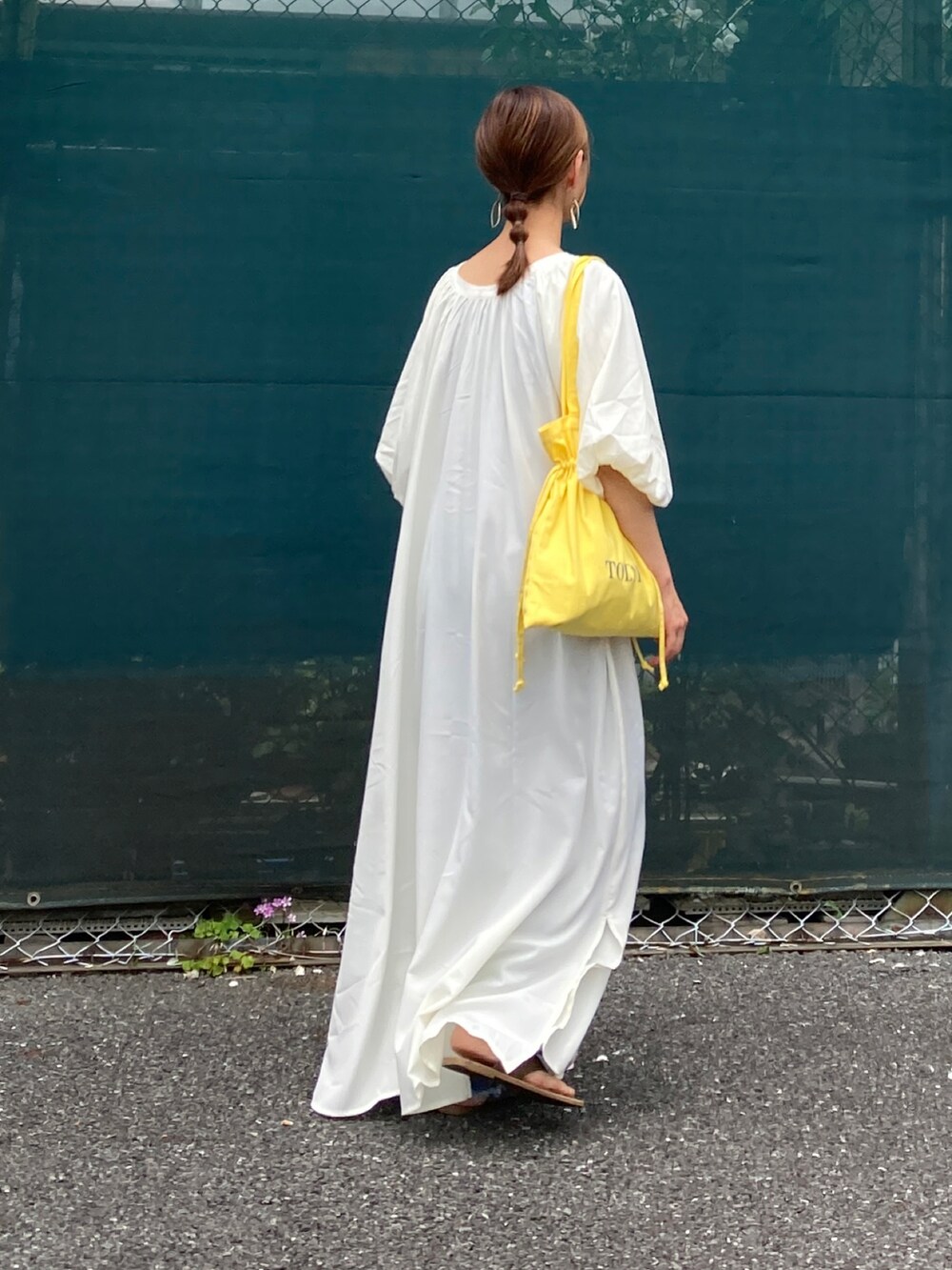 ホワイト系のワンピース、イエロー系のトートバッグ、ブルー系のデニムパンツを着用したレディースの夏コーディネートの5枚目の写真