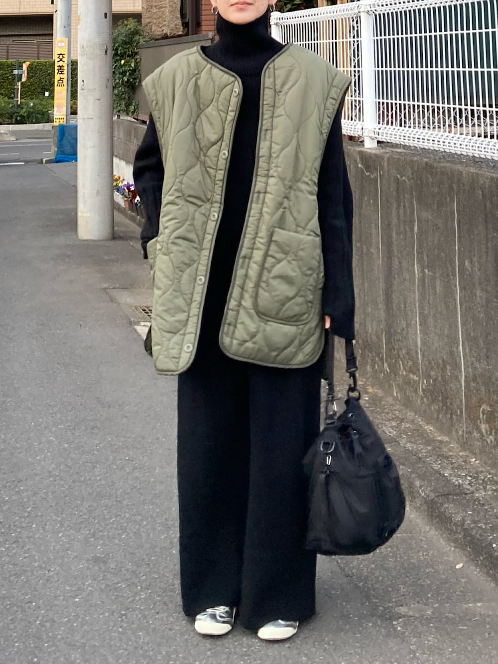 グリーン系のブルゾン、ブラック系のワンピース、ブラック系のショルダーバッグを着用したレディースの冬コーディネートの2枚目の写真