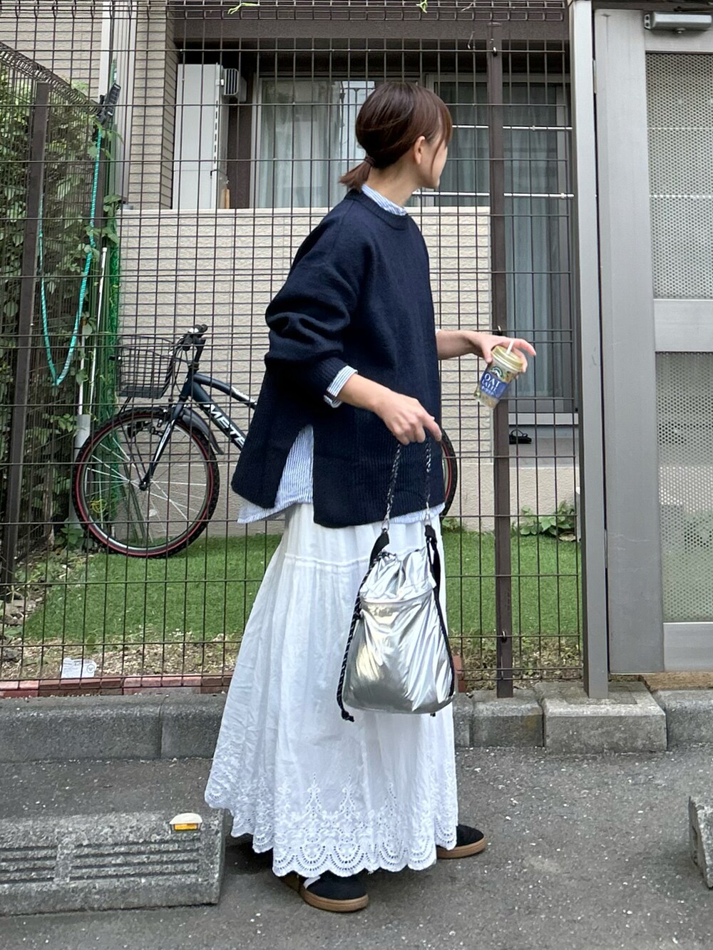 ブルー系のニット/セーター、シルバー系のショルダーバッグ、ホワイト系のスカートを着用したレディースの秋コーディネートの5枚目の写真