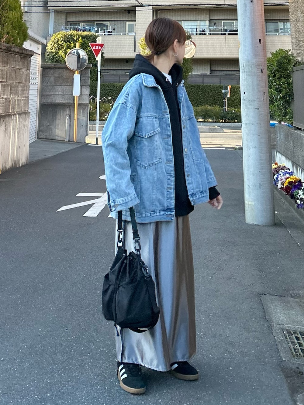 ブルー系のデニムジャケット、シルバー系のスカート、ブラック系のショルダーバッグを着用したレディースの春コーディネートの2枚目の写真