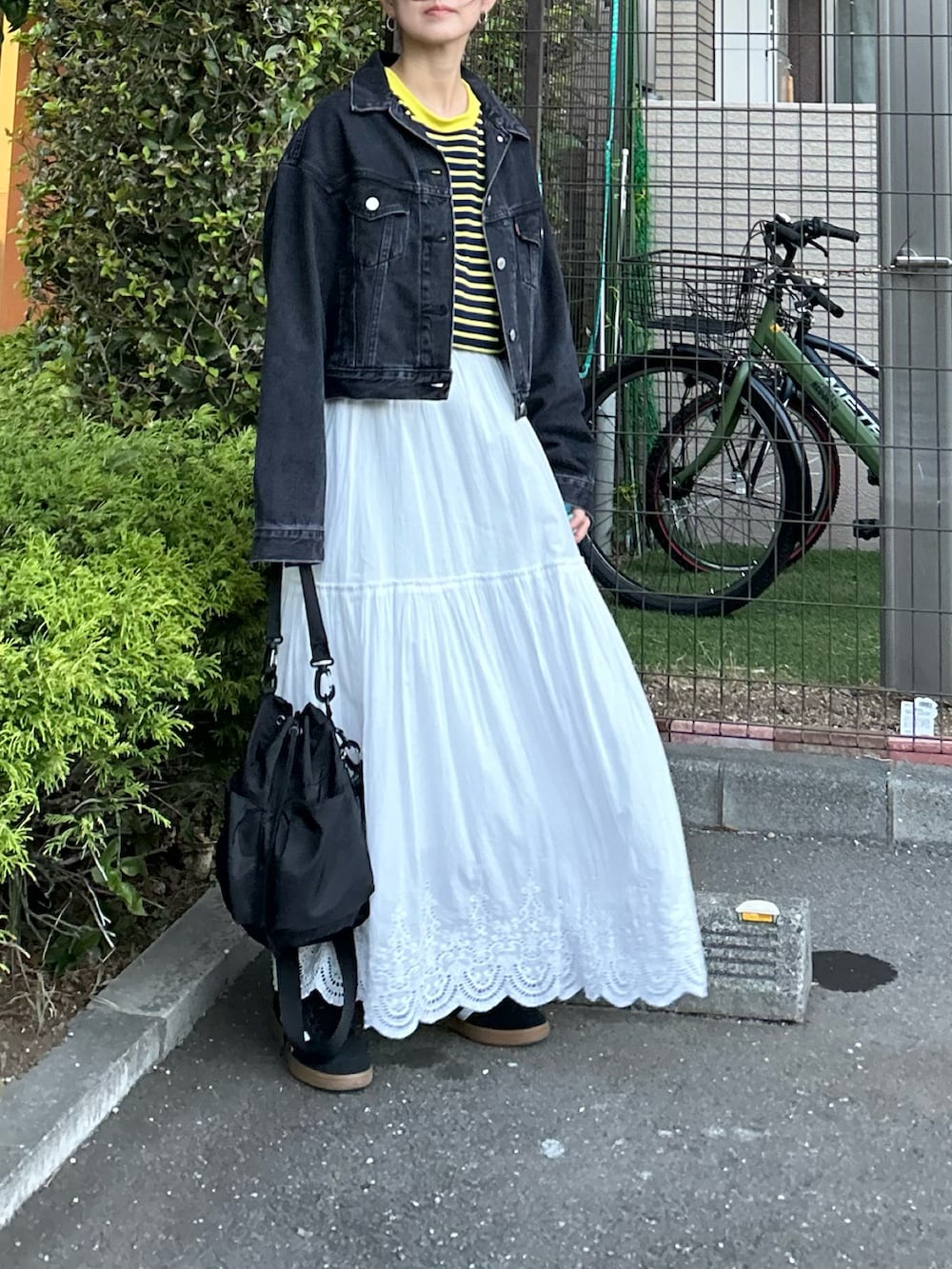 ブラック系のデニムジャケット、ブルー系のTシャツ/カットソー、ホワイト系のスカートを着用したレディースの秋コーディネートの2枚目の写真