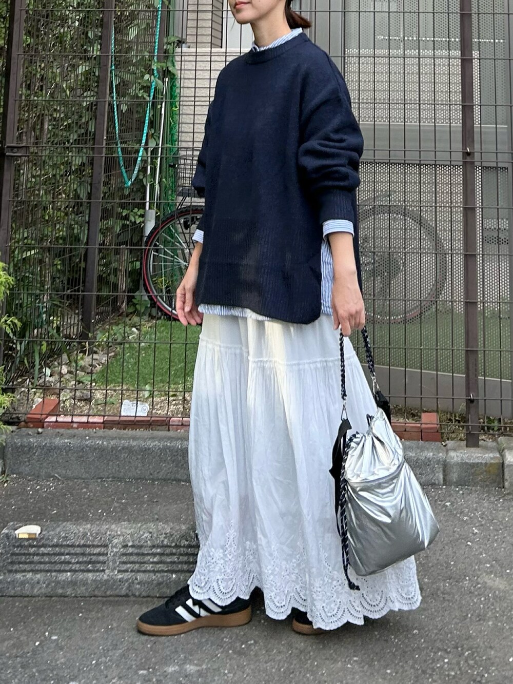 ブルー系のニット/セーター、シルバー系のショルダーバッグ、ホワイト系のスカートを着用したレディースの秋コーディネートの3枚目の写真