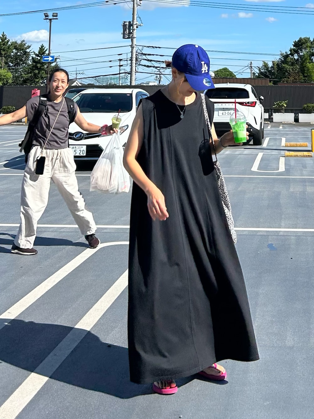 ブラック系のワンピース、パープル系のサンダル、ブルー系のキャップを着用したレディースの夏コーディネートの3枚目の写真