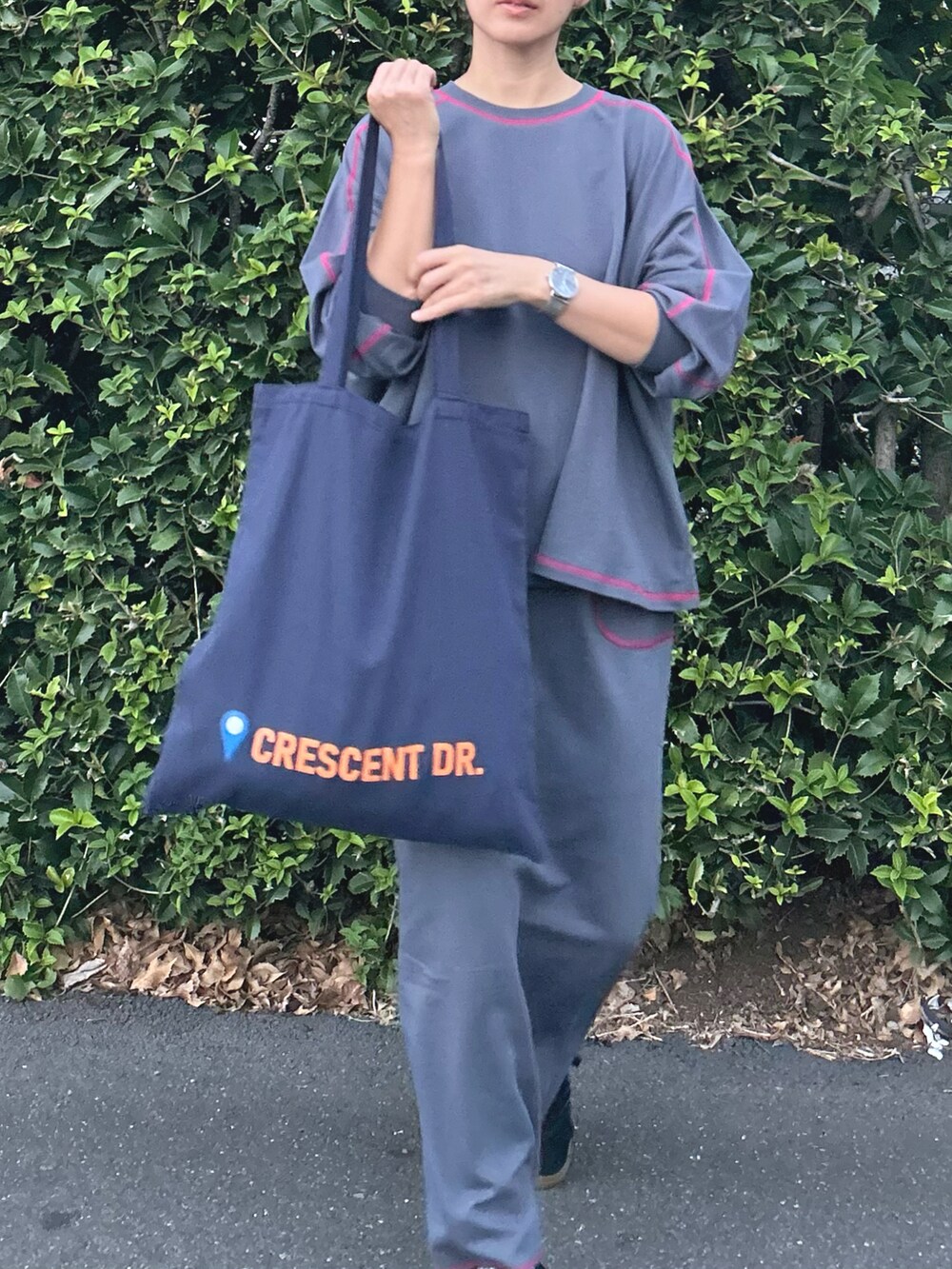 グレー系のTシャツ/カットソー、グレー系のスカート、ブルー系のトートバッグを着用したレディースの秋コーディネートの4枚目の写真