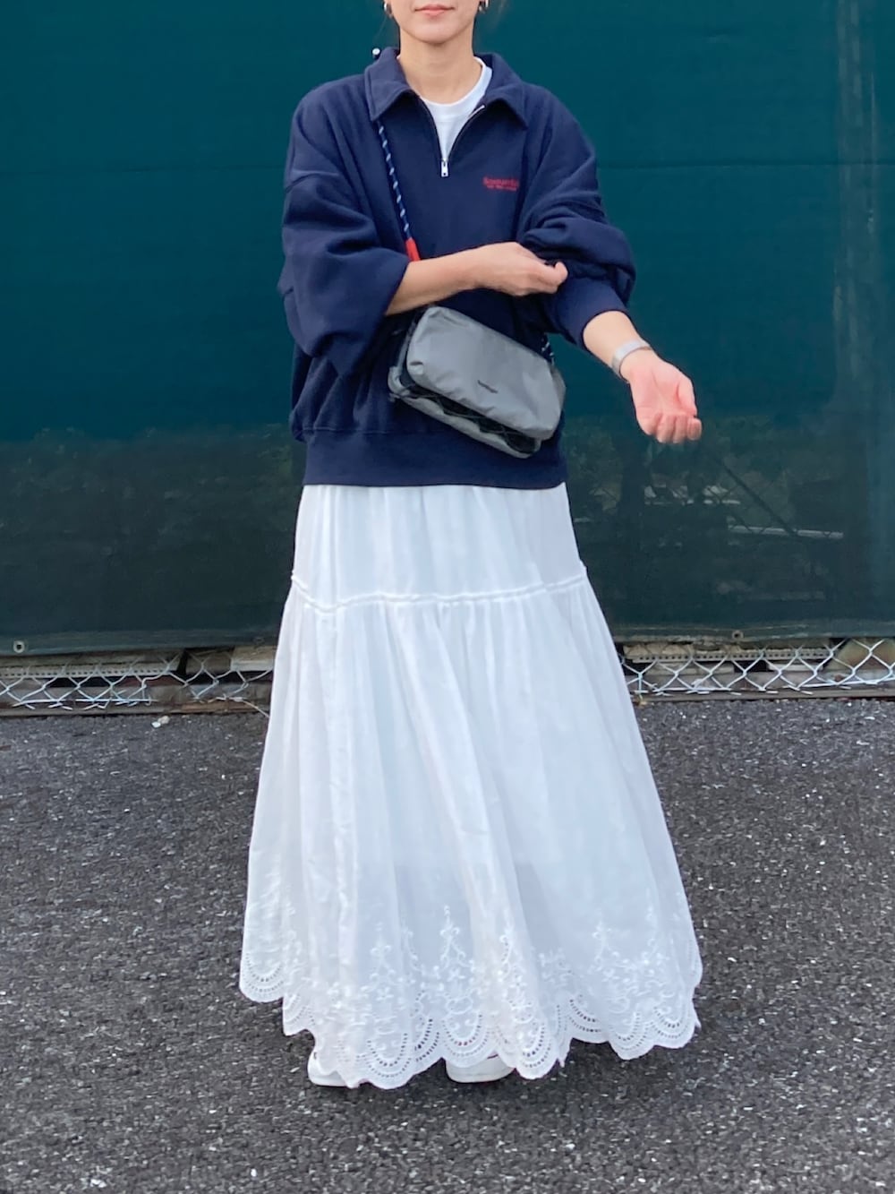 ブルー系のスウェット、ホワイト系のスカート、グレー系のショルダーバッグを着用したレディースの秋コーディネートの2枚目の写真