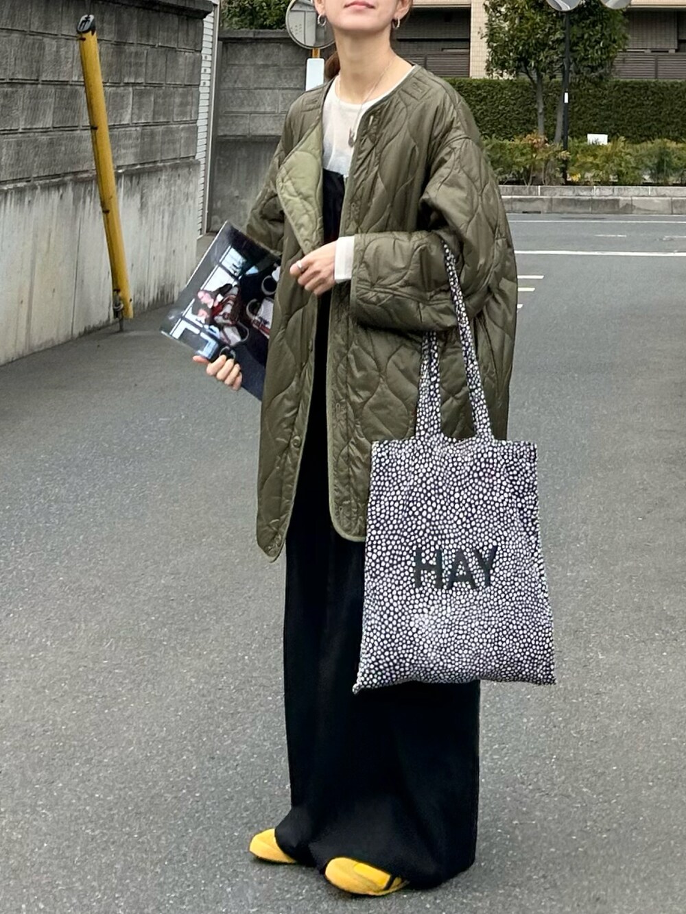 グリーン系のノーカラージャケット、ホワイト系のニット/セーター、ブラック系のサロペット/オーバーオールを着用したレディースの春コーディネートの2枚目の写真