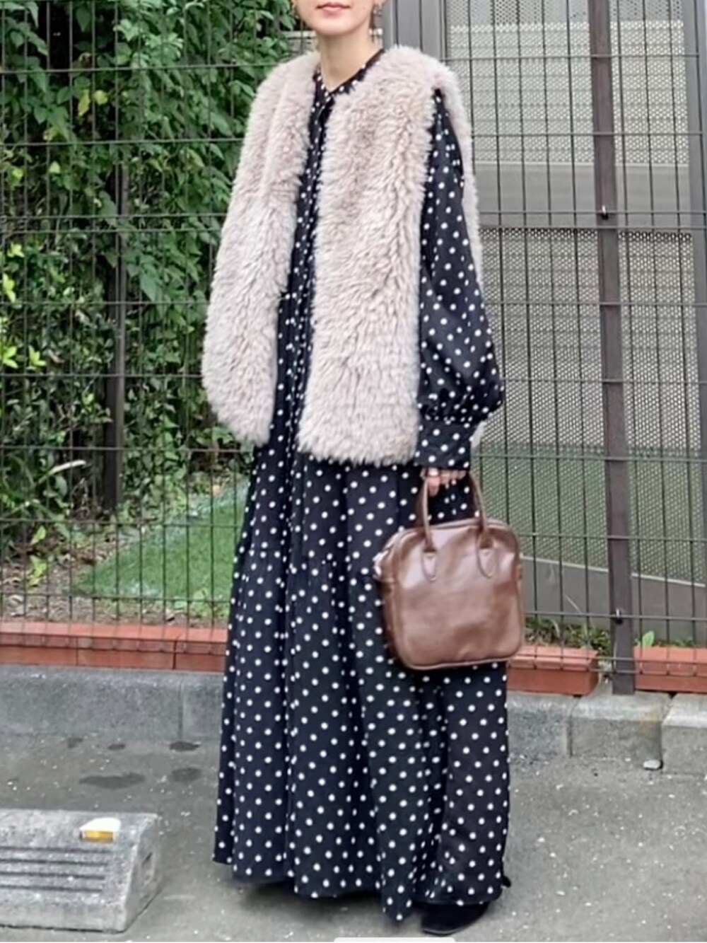 ベージュ系のベスト、ブラック系のシャツワンピース、ブラウン系のショルダーバッグを着用したレディースの秋コーディネートの2枚目の写真