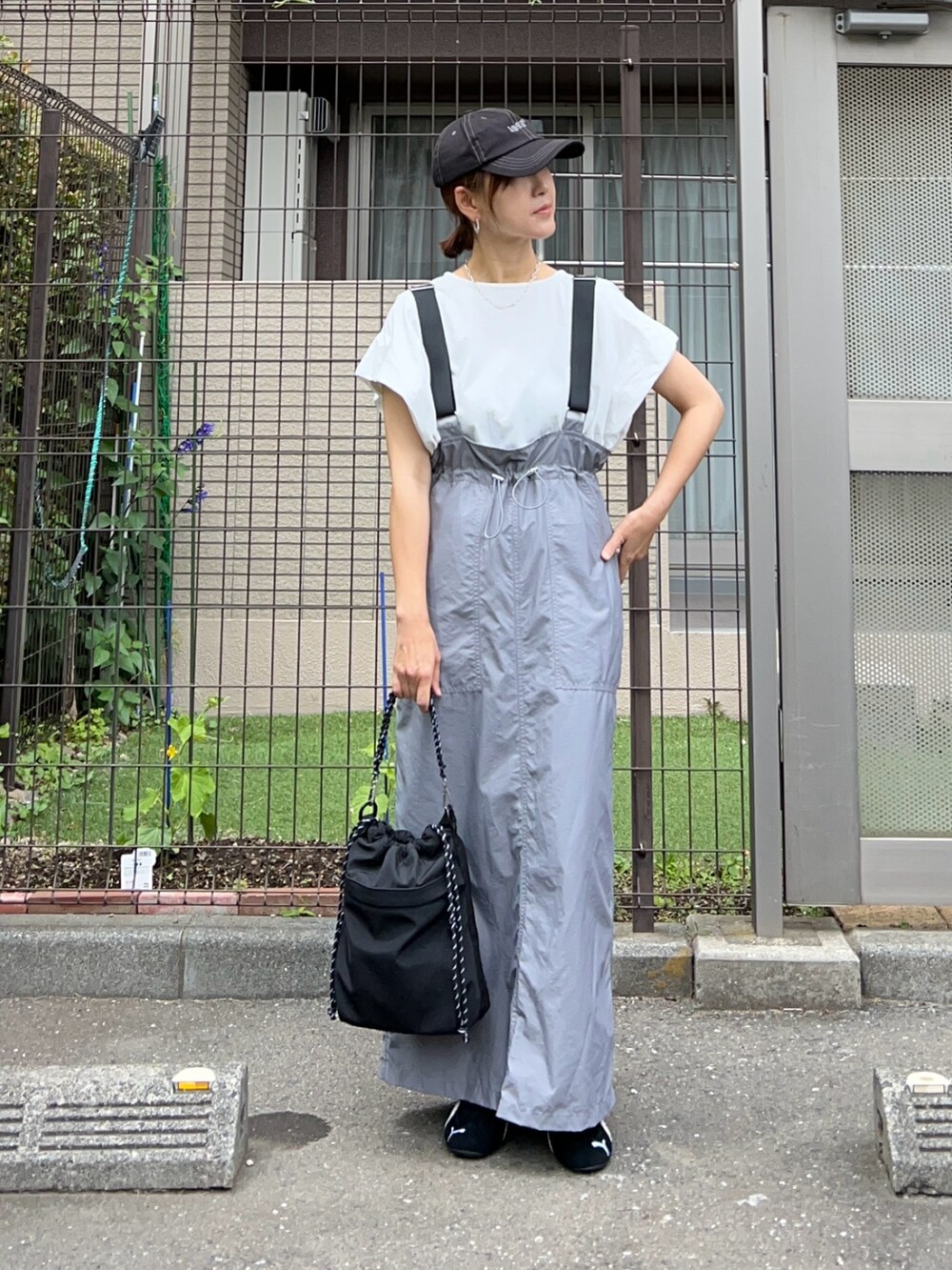 グレー系のジャンパースカート、ブラック系のトートバッグ、ブラック系のスニーカーを着用したレディースの夏コーディネートの3枚目の写真