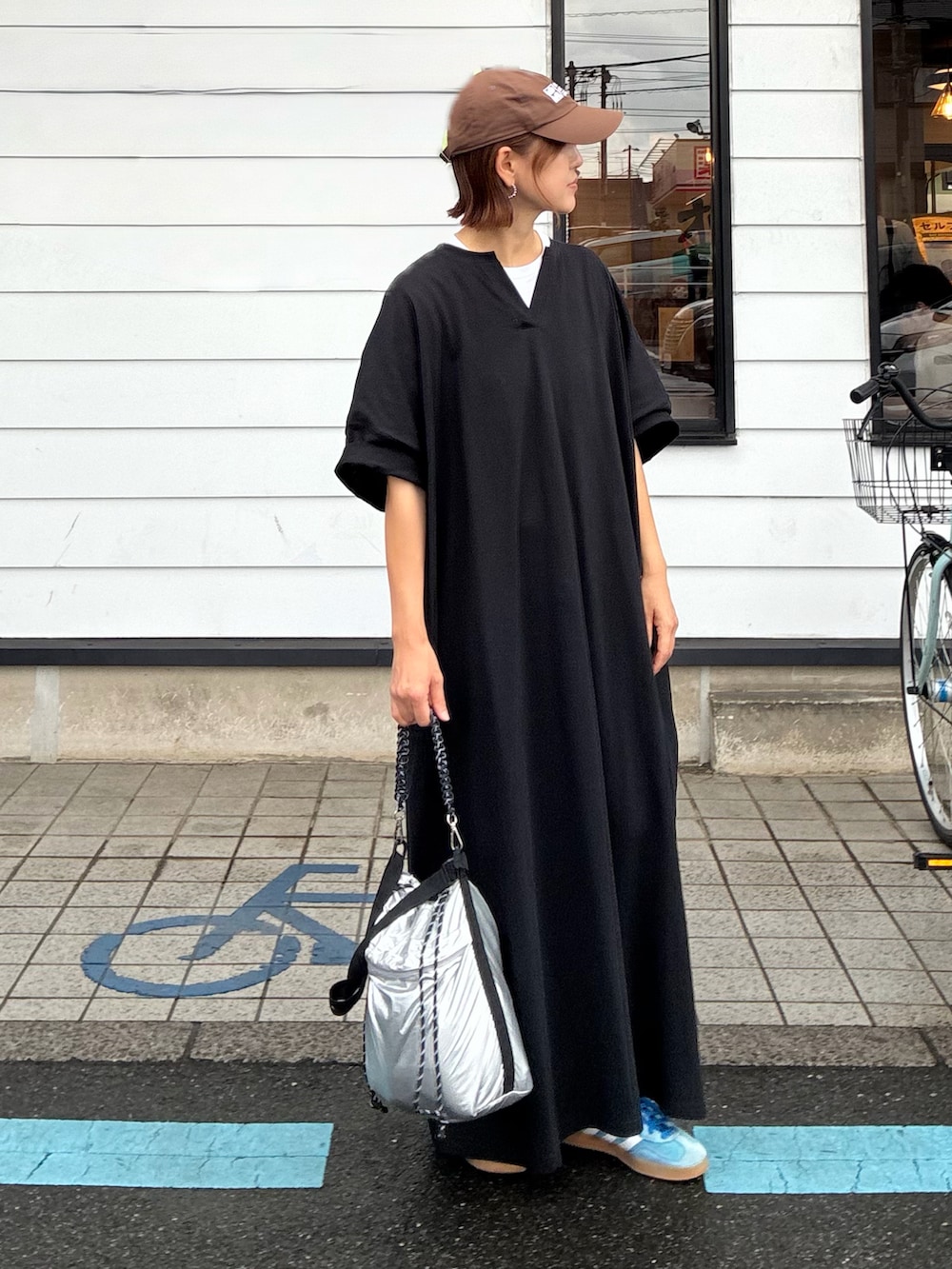 ブラック系のワンピース、シルバー系のショルダーバッグ、ブルー系のスニーカーを着用したレディースの秋コーディネートの3枚目の写真