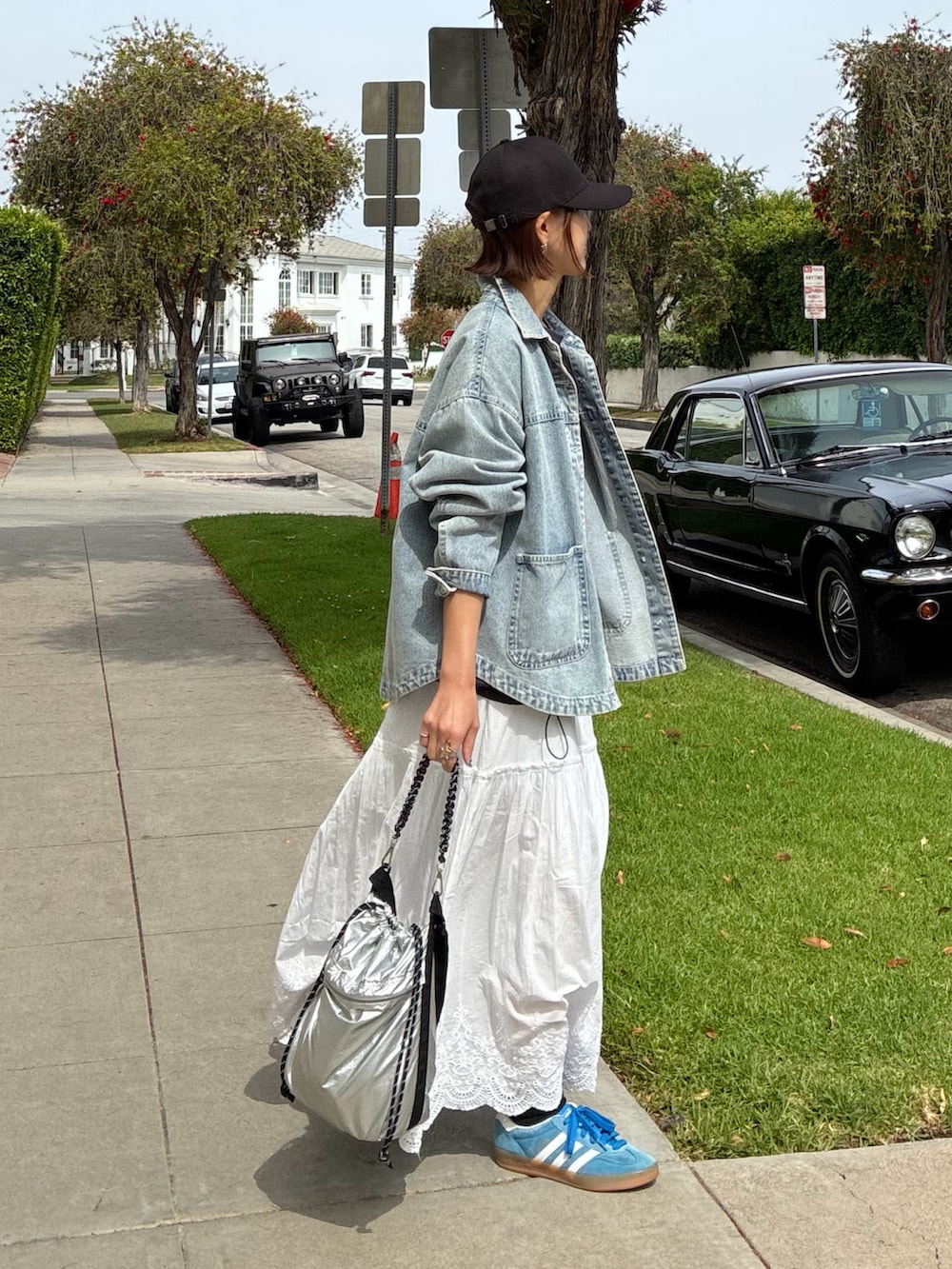 ブルー系のデニムジャケット、シルバー系のトートバッグ、ホワイト系のスカートを着用したレディースの春コーディネートの2枚目の写真