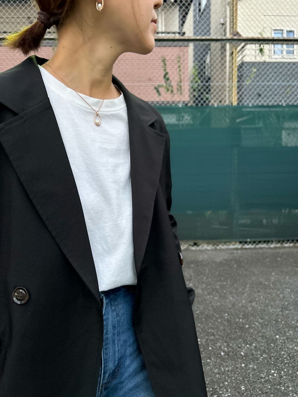 ブラック系のテーラードジャケット、ブルー系のデニムパンツ、グリーン系のトートバッグを着用したレディースの秋コーディネートの3枚目の写真