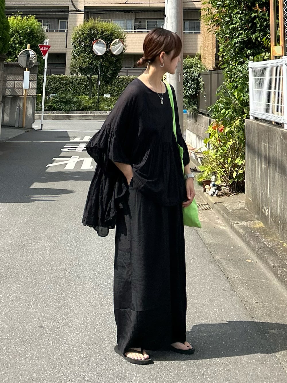 グリーン系のトートバッグ、ブラック系のシャツ/ブラウスを着用したレディースの夏コーディネートの2枚目の写真