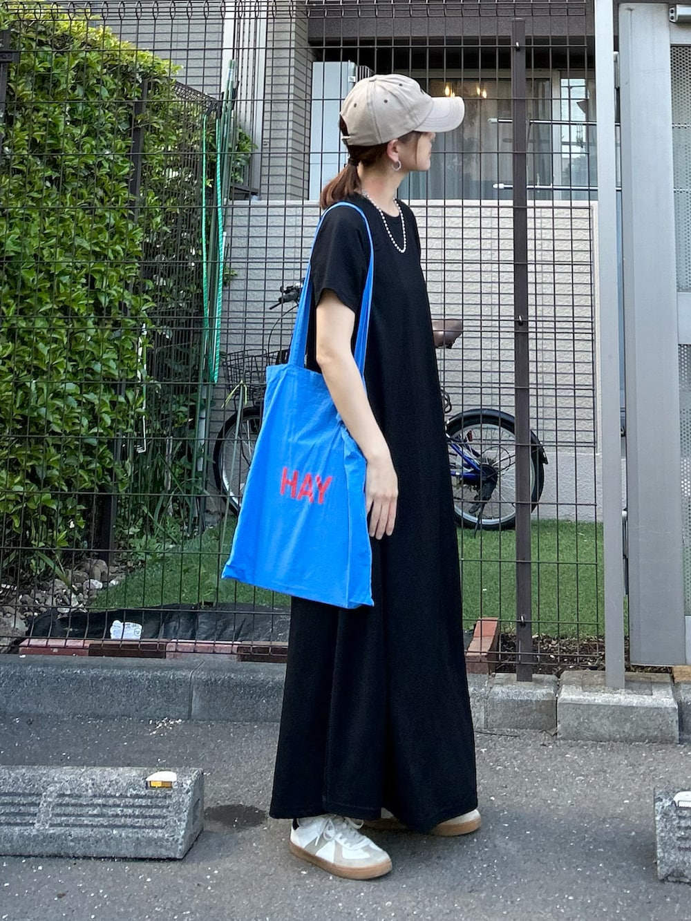 ブラック系のワンピース、ホワイト系のスニーカー、ベージュ系のキャップを着用したレディースの春コーディネートの2枚目の写真