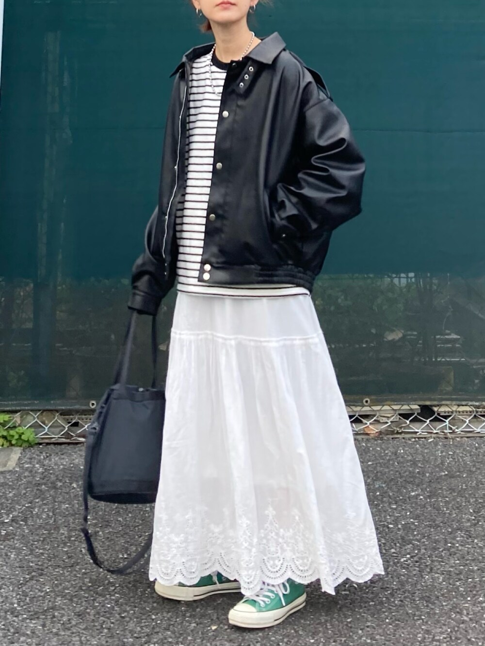 ブラック系のブルゾン、ブラック系のTシャツ/カットソー、ホワイト系のスカートを着用したレディースの春コーディネートの2枚目の写真