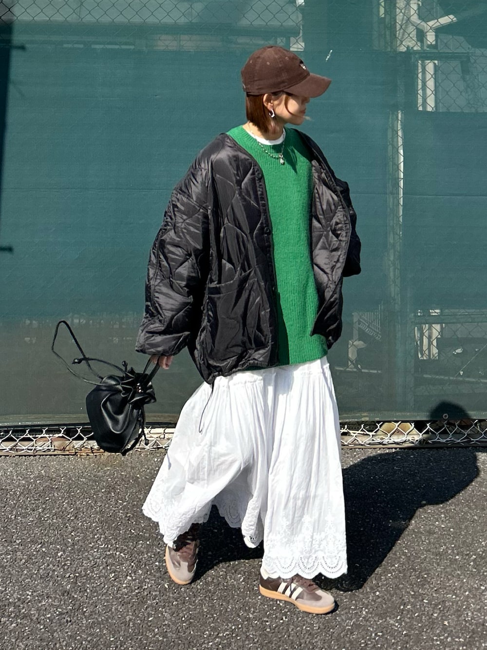 ブラック系のブルゾン、グリーン系のニット/セーター、ホワイト系のスカートを着用したレディースの冬コーディネートの4枚目の写真