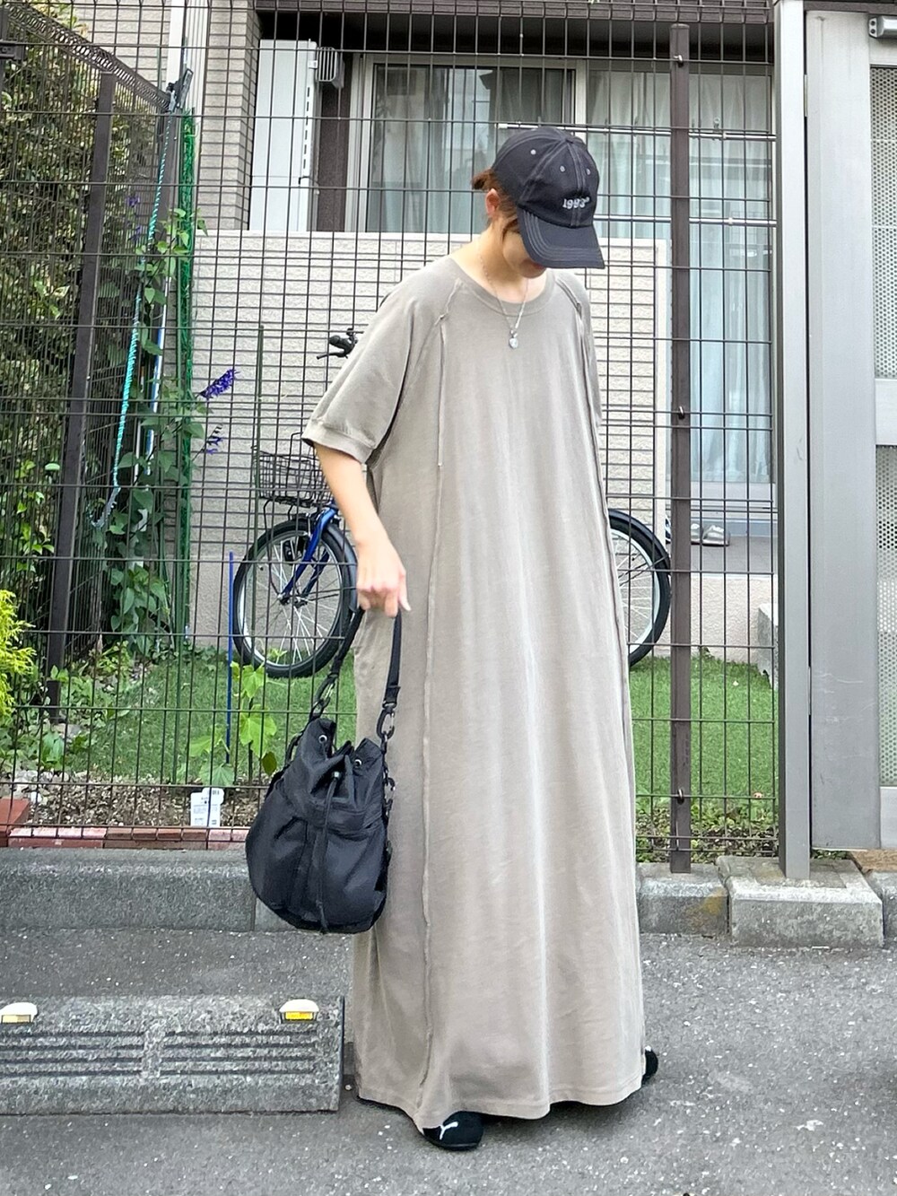 グリーン系のワンピース、ブラック系のショルダーバッグ、ブラック系のスニーカーを着用したレディースの春コーディネートの2枚目の写真