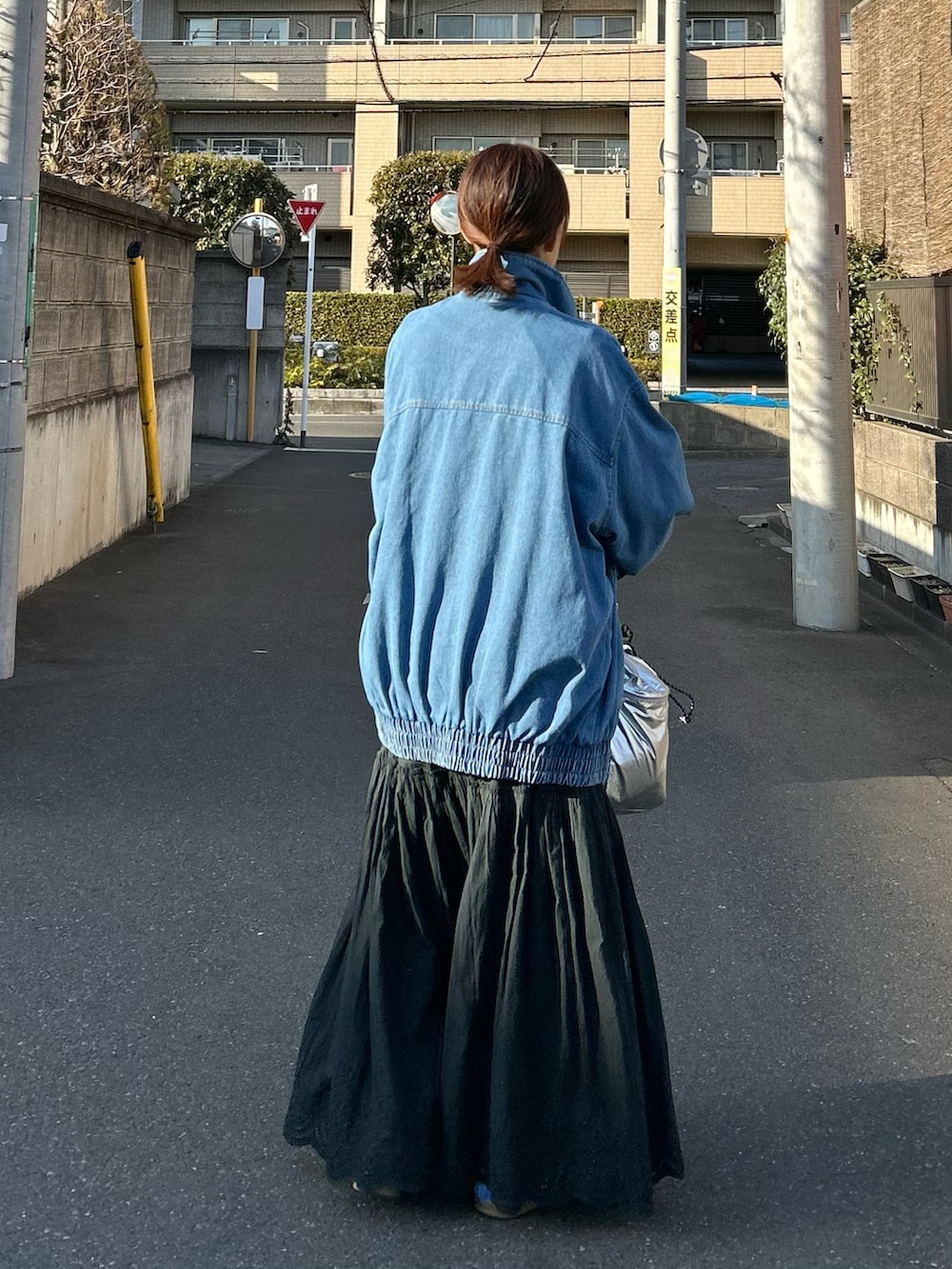 ブルー系のデニムジャケット、ブラック系のスカート、シルバー系のショルダーバッグを着用したレディースの春コーディネートの5枚目の写真