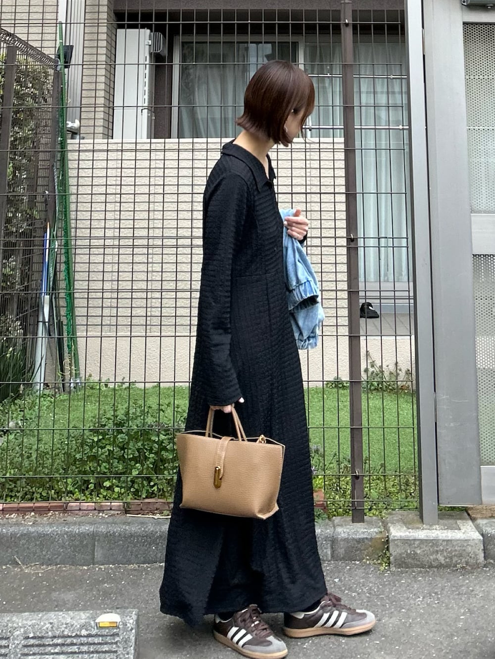 ブルー系のデニムジャケット、ブラック系のワンピース、ブラウン系のハンドバッグを着用したレディースの冬コーディネートの5枚目の写真