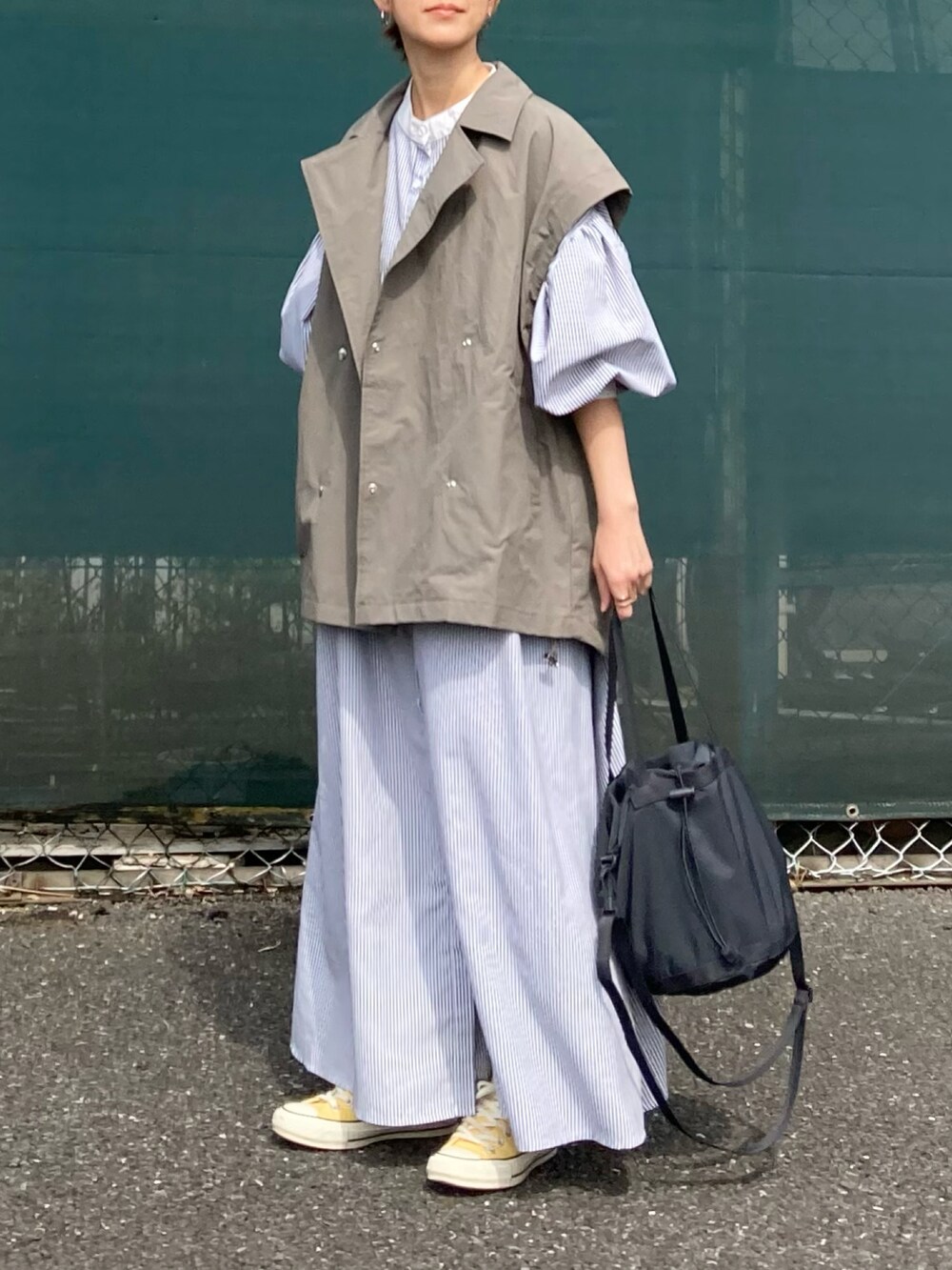 グレー系のミリタリージャケット、ブラック系のワンピース、ブラック系のバッグを着用したレディースの春コーディネートの2枚目の写真