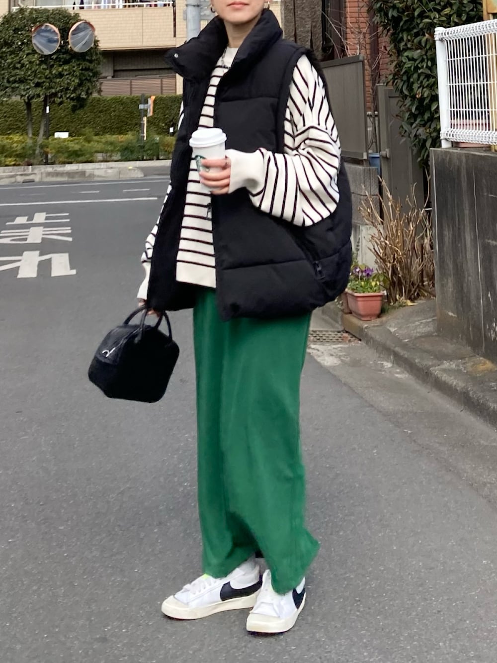 ブラック系のダウンベスト、ホワイト系のニット/セーター、グリーン系のスカートを着用したレディースの冬コーディネートの3枚目の写真