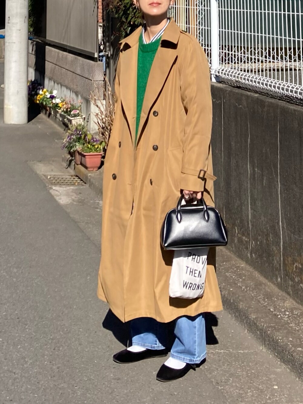 イエロー系のトレンチコートを着用したレディースの冬コーディネートの4枚目の写真