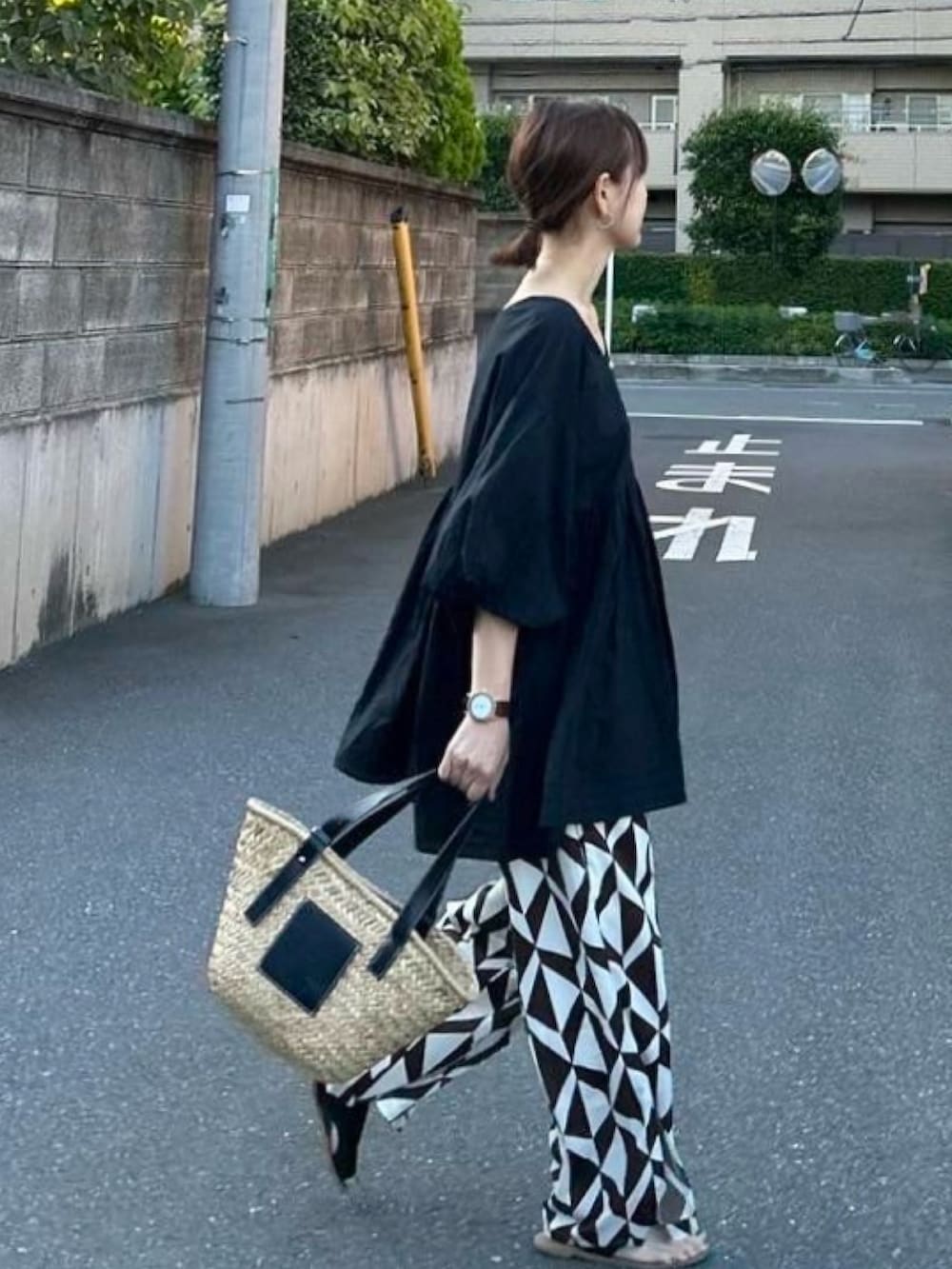 ブラック系のチュニック、ブラウン系のその他パンツ、ブラック系のかごバッグを着用したレディースの夏コーディネートの2枚目の写真