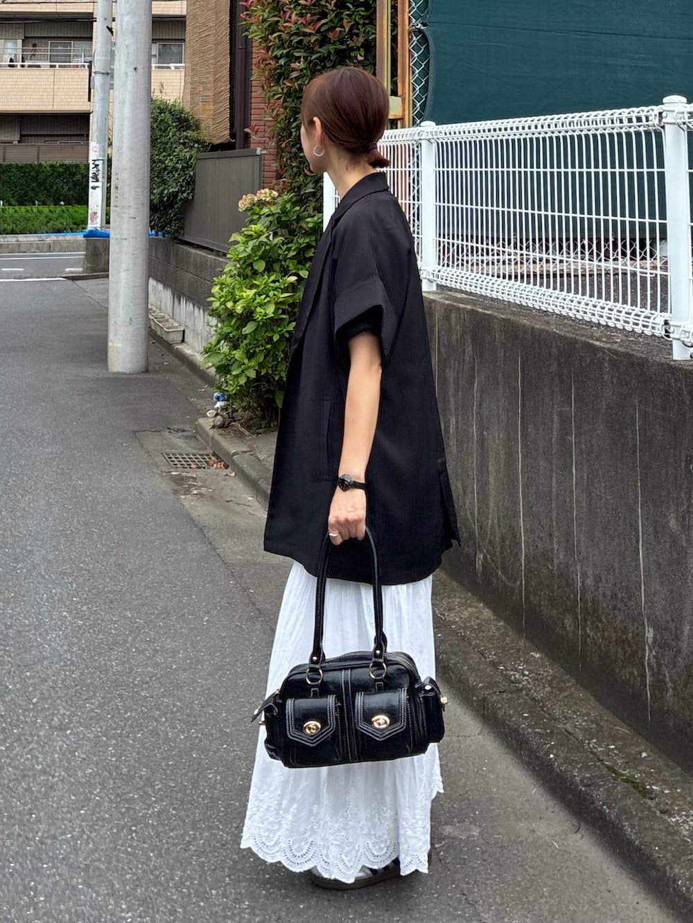 ブラック系のテーラードジャケット、グレー系のTシャツ/カットソー、ホワイト系のスカートを着用したレディースの秋コーディネートの3枚目の写真