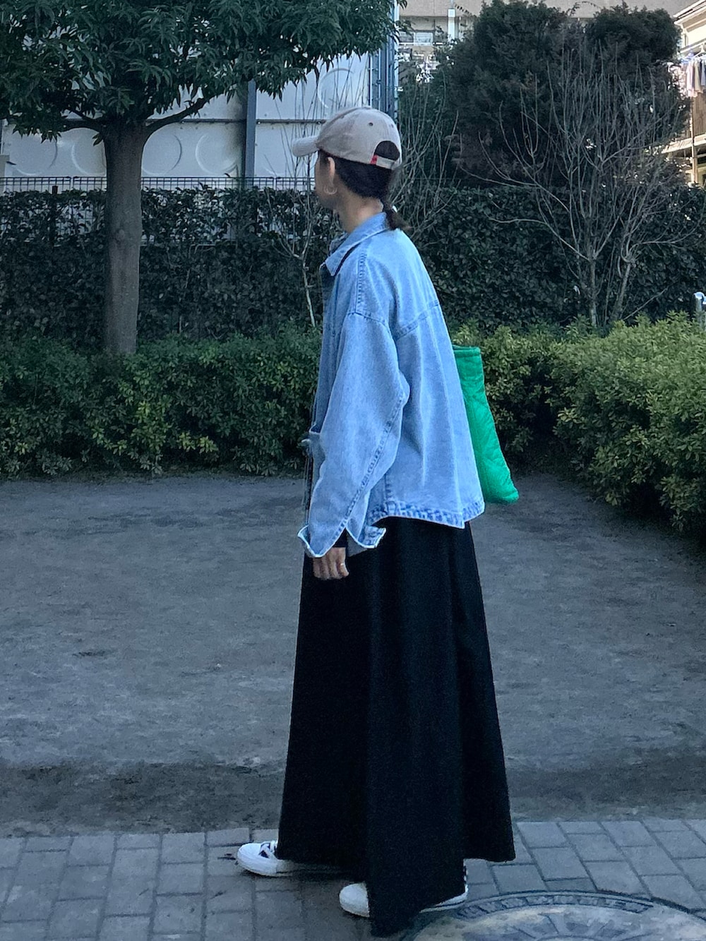 ブルー系のデニムジャケット、ブラック系のワンピース、グリーン系のトートバッグを着用したレディースの春コーディネートの4枚目の写真