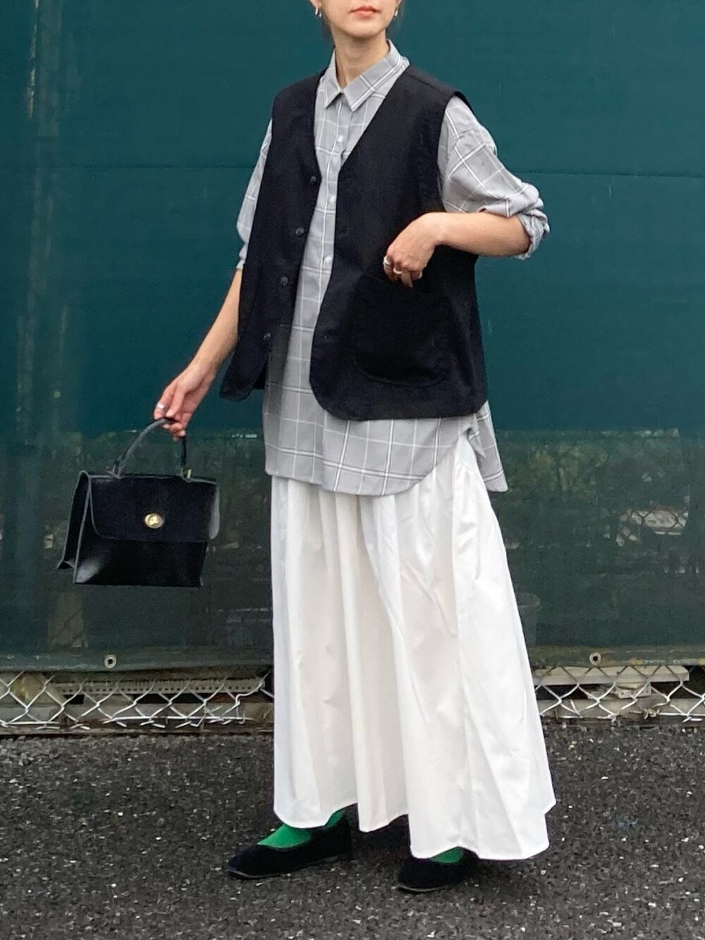 ブラック系のベスト、ホワイト系のスカート、ブラウン系のシャツ/ブラウスを着用したレディースの夏コーディネートの2枚目の写真