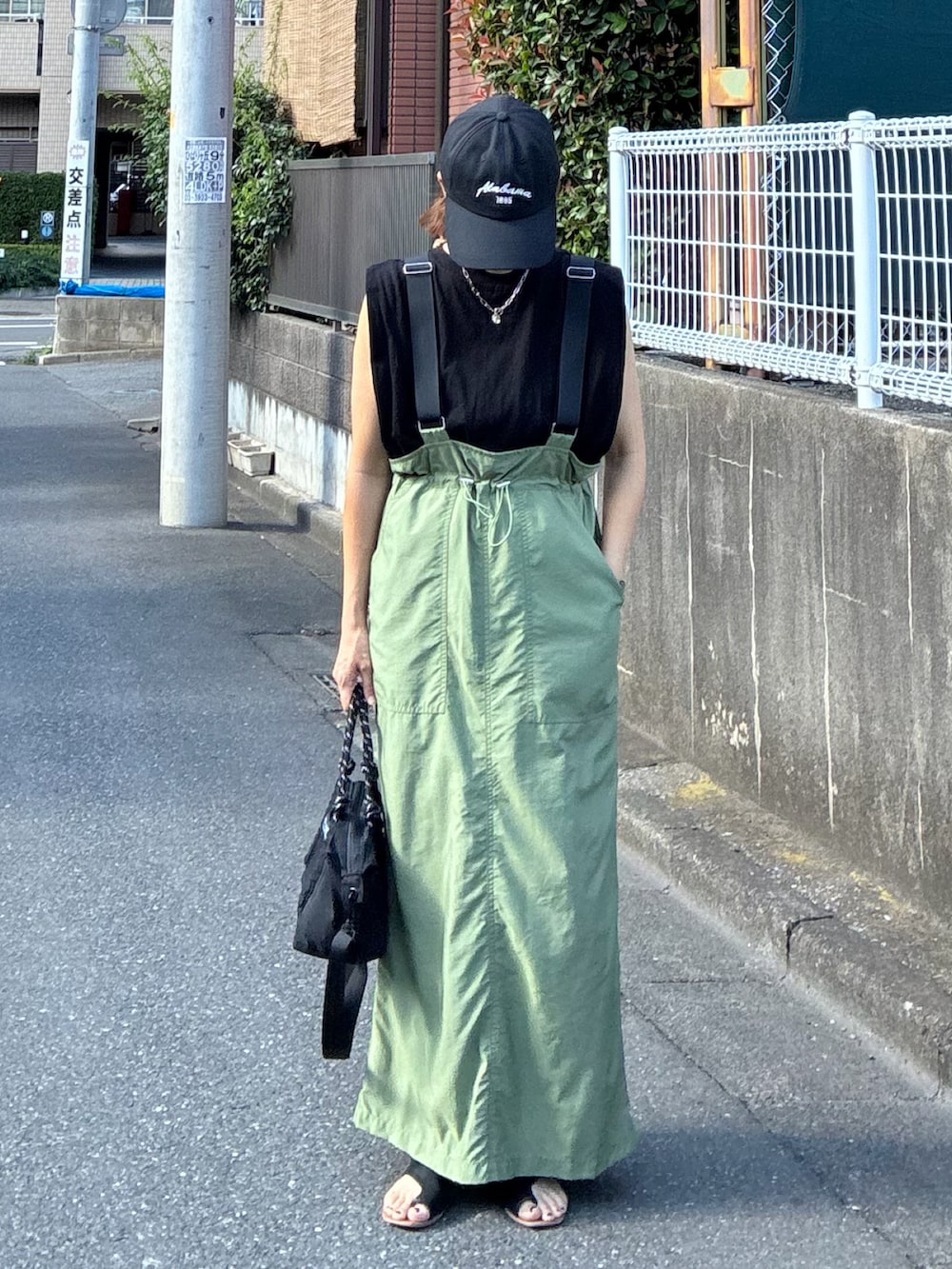 ブラック系のTシャツ/カットソー、グリーン系のジャンパースカート、ブラック系のトートバッグを着用したレディースの夏コーディネートの2枚目の写真