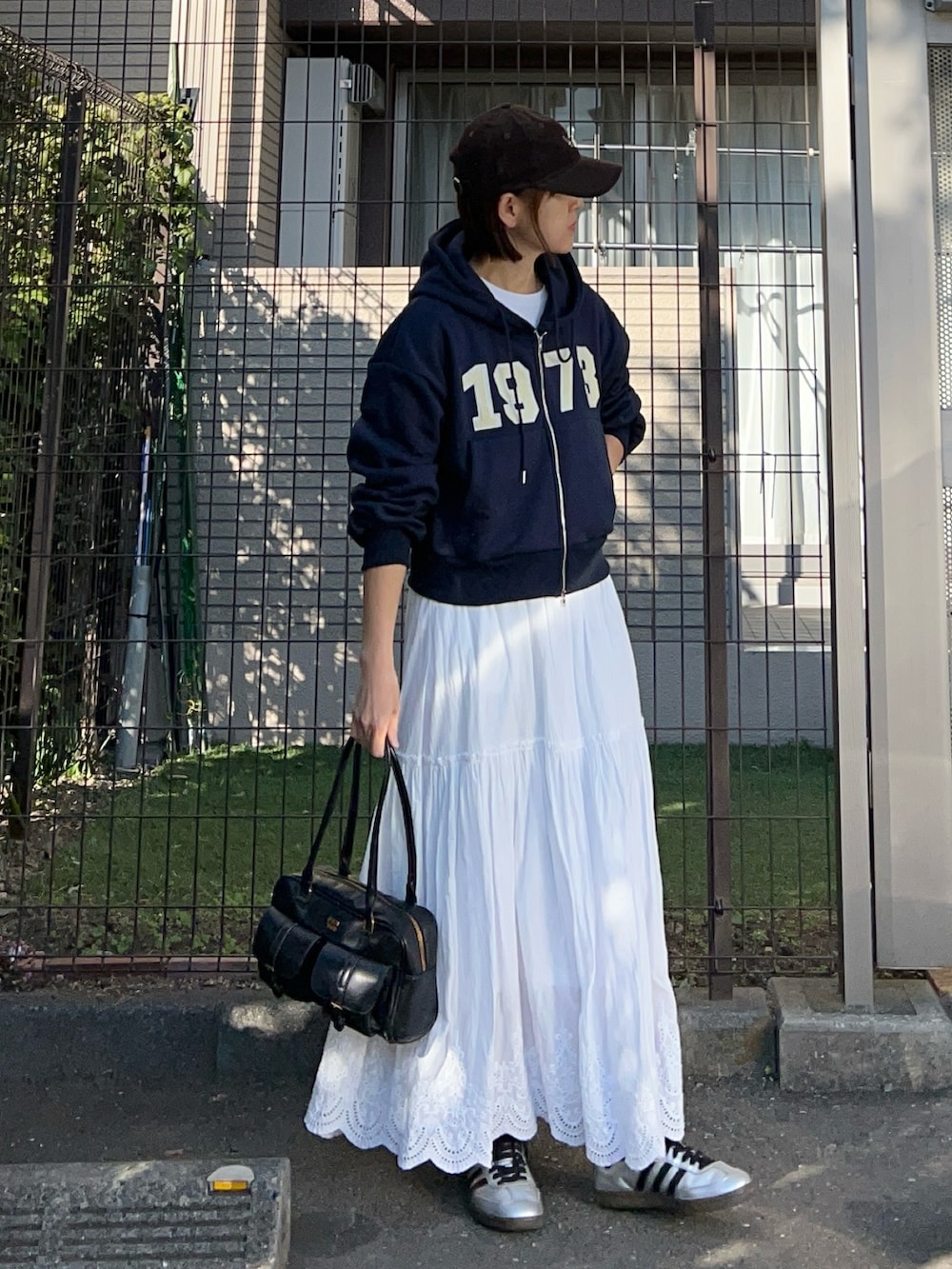 ブルー系のパーカー、ホワイト系のスカート、ブラック系のハンドバッグを着用したレディースの冬コーディネートの2枚目の写真