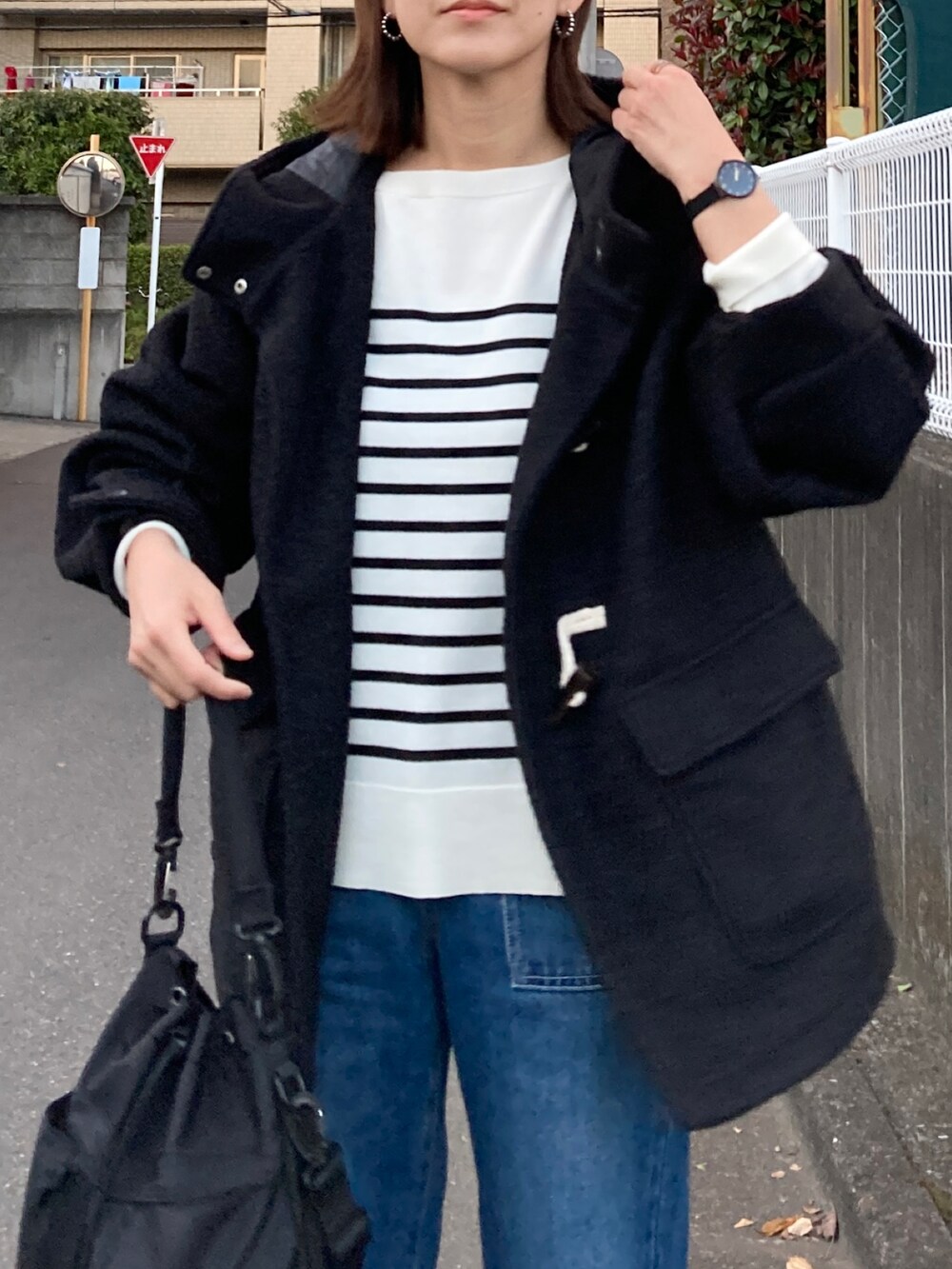 ブラック系のダッフルコート、ホワイト系のニット/セーター、ブラック系のショルダーバッグを着用したレディースの冬コーディネートの5枚目の写真