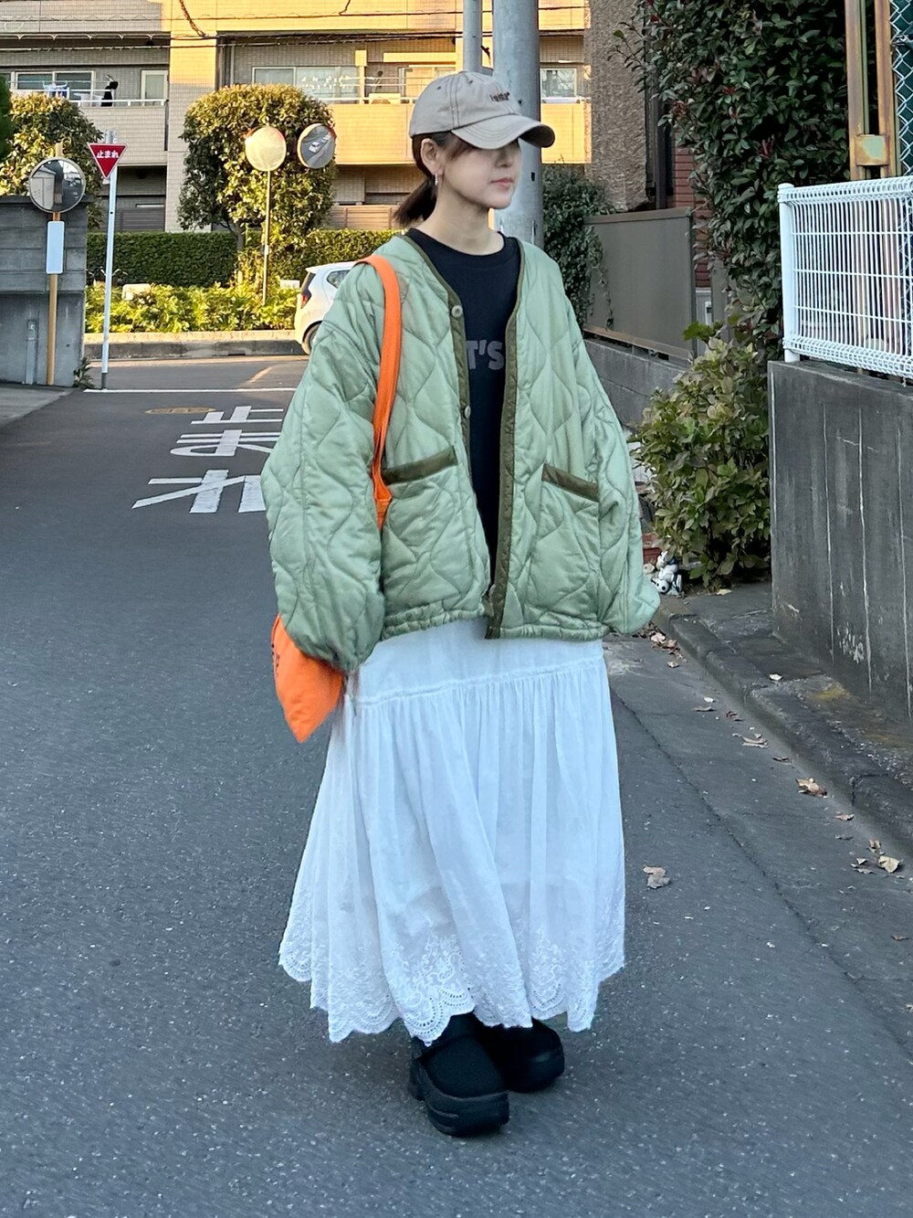 ブラック系のTシャツ/カットソー、グリーン系のノーカラージャケット、ホワイト系のスカートを着用したレディースの冬コーディネートの2枚目の写真